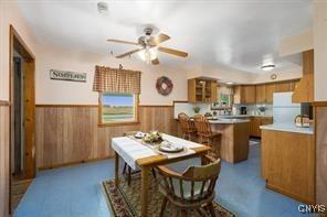 dining room with ceiling fan and wooden walls