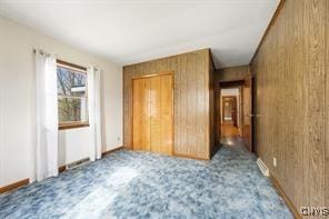 unfurnished bedroom featuring light carpet and wood walls