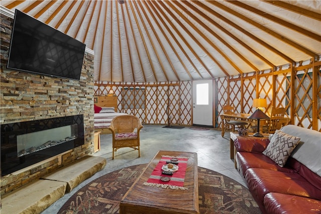 living room featuring tile patterned flooring, a stone fireplace, and high vaulted ceiling