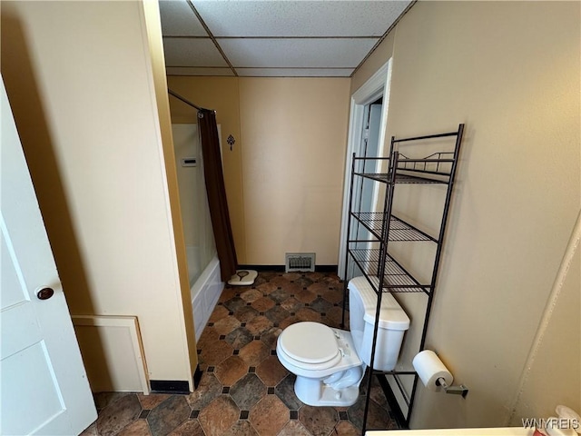 bathroom featuring a drop ceiling, shower / bath combo, and toilet