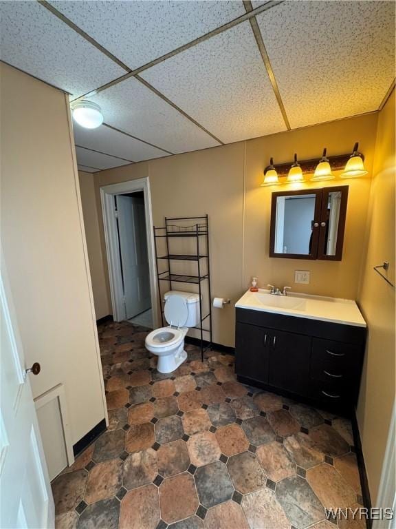 bathroom featuring vanity, toilet, and a drop ceiling