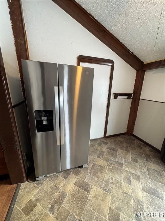 kitchen with vaulted ceiling, stainless steel fridge with ice dispenser, and a textured ceiling