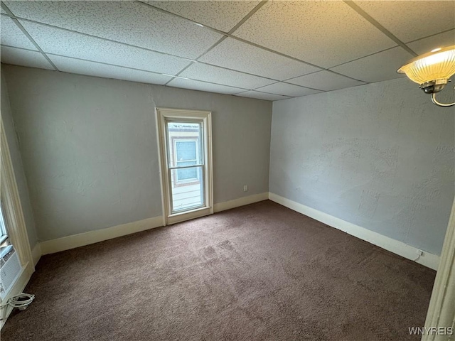 carpeted spare room with a drop ceiling