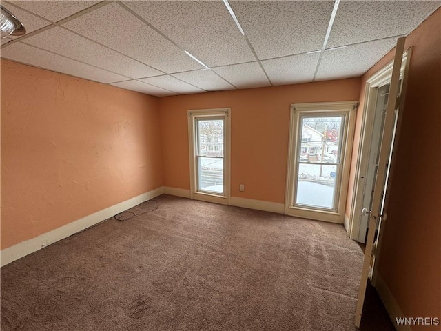 carpeted empty room with a wealth of natural light and a drop ceiling