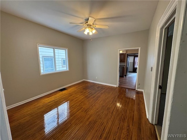 spare room with dark wood-type flooring and ceiling fan