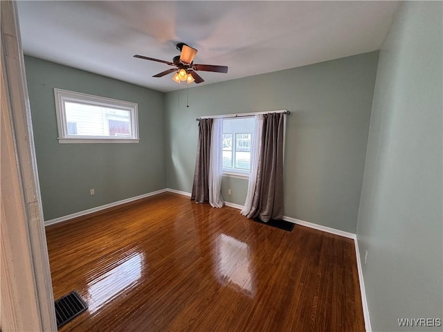 empty room with hardwood / wood-style flooring, a wealth of natural light, and ceiling fan