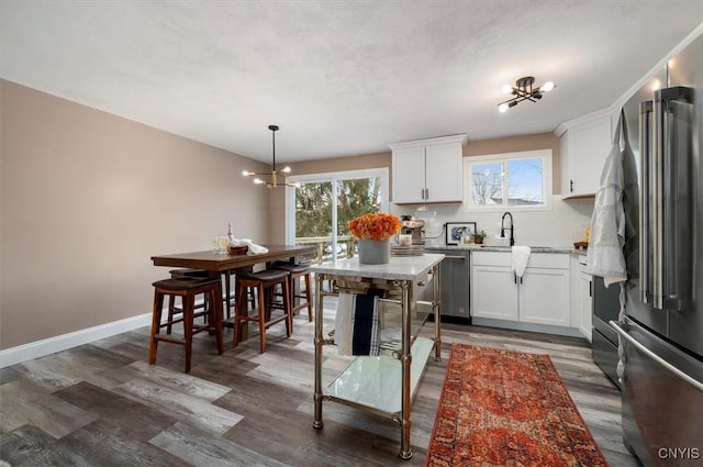 kitchen with pendant lighting, a notable chandelier, stainless steel appliances, and white cabinets