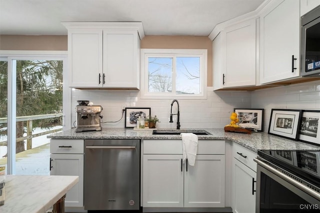 kitchen with white cabinetry, sink, stainless steel appliances, and light stone countertops