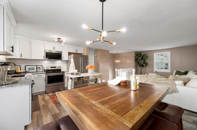 dining area featuring sink, light hardwood / wood-style flooring, and a notable chandelier