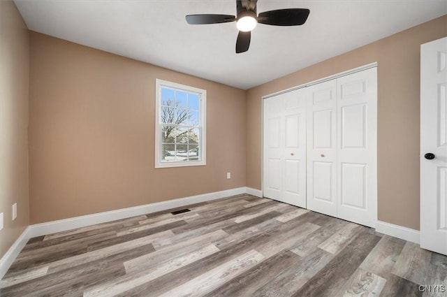 unfurnished bedroom with ceiling fan, a closet, and light wood-type flooring