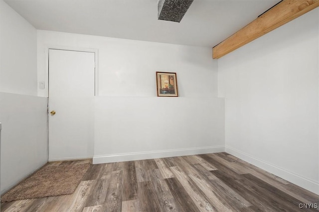 empty room featuring hardwood / wood-style flooring and beamed ceiling