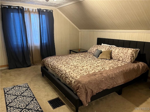 bedroom with lofted ceiling, light carpet, and wooden walls