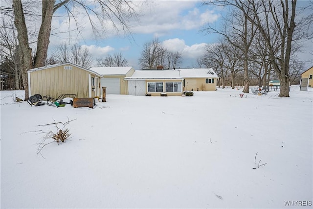 snow covered rear of property with a garage