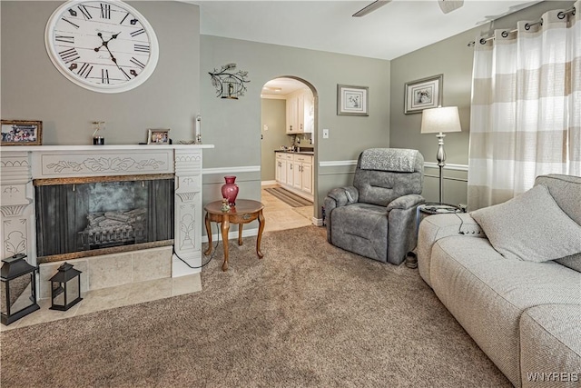 living room featuring ceiling fan, light carpet, and a fireplace