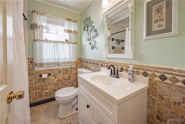 bathroom with ornamental molding, vanity, toilet, and tile walls