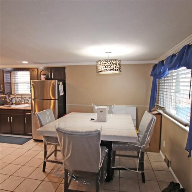 dining room featuring crown molding, light tile patterned flooring, and sink