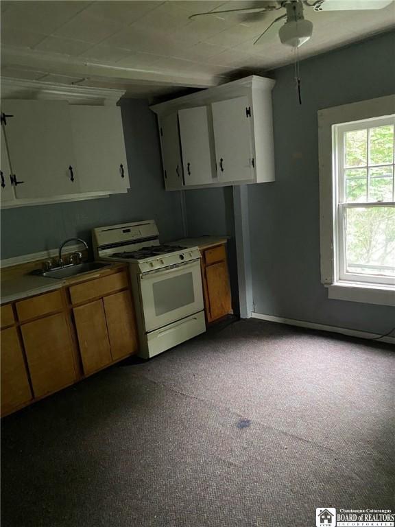 kitchen featuring white cabinetry, white range with gas cooktop, sink, and ceiling fan