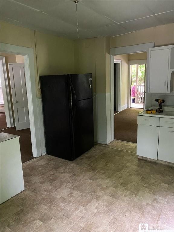 kitchen with black fridge and white cabinets