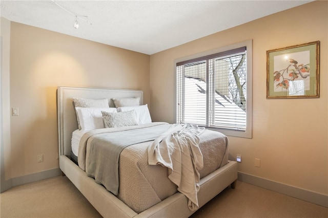 carpeted bedroom featuring rail lighting