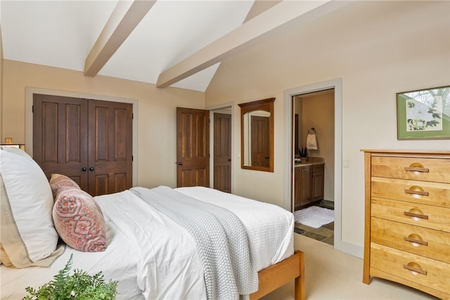 carpeted bedroom with ensuite bathroom, a closet, and vaulted ceiling with beams