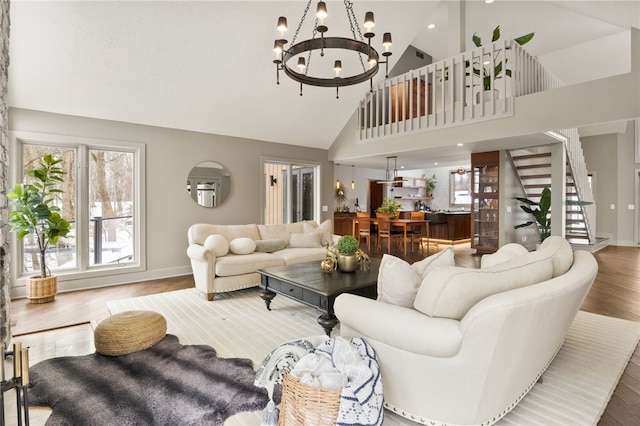 living room featuring hardwood / wood-style floors, high vaulted ceiling, and a chandelier