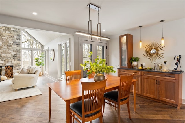 dining room with dark wood-type flooring, lofted ceiling, and a healthy amount of sunlight