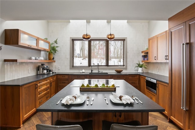 kitchen featuring a breakfast bar, sink, tasteful backsplash, a center island, and hardwood / wood-style flooring