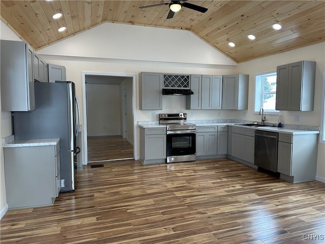 kitchen with lofted ceiling, appliances with stainless steel finishes, range hood, and gray cabinetry