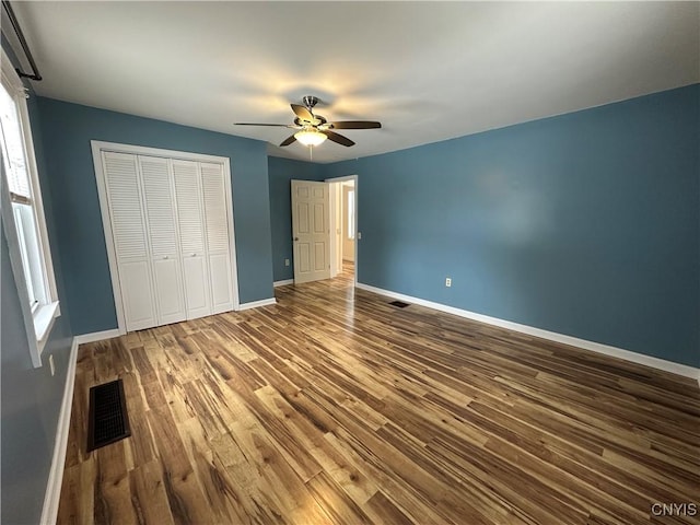 unfurnished bedroom with hardwood / wood-style floors, ceiling fan, and a closet