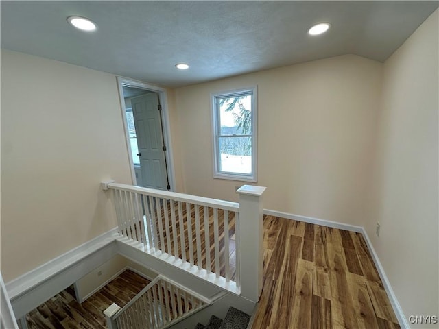 staircase with hardwood / wood-style floors and vaulted ceiling