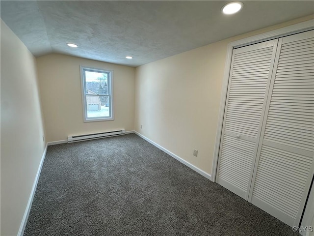 unfurnished bedroom with a baseboard heating unit, dark colored carpet, a textured ceiling, vaulted ceiling, and a closet