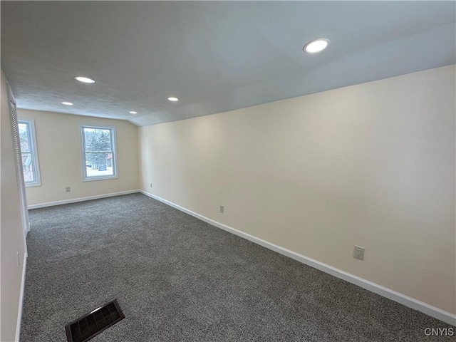 carpeted empty room featuring vaulted ceiling