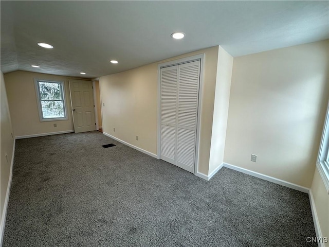 unfurnished bedroom featuring a closet and dark colored carpet