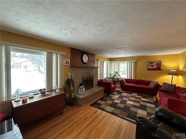 living room featuring a fireplace, wood-type flooring, and a textured ceiling