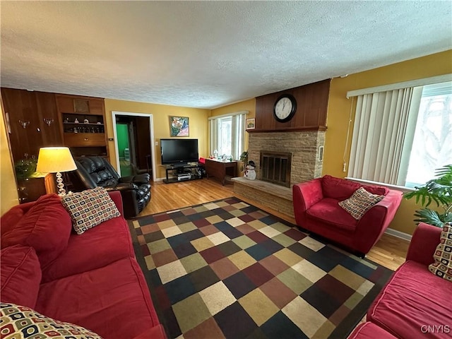 living room featuring wood-type flooring, a fireplace, and a textured ceiling