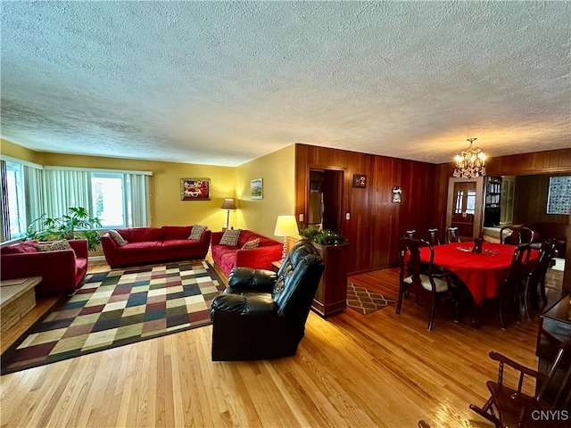 living room with a chandelier, a textured ceiling, and light wood-type flooring