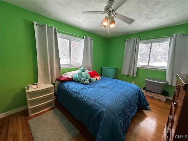 bedroom with dark wood-type flooring, ceiling fan, and multiple windows