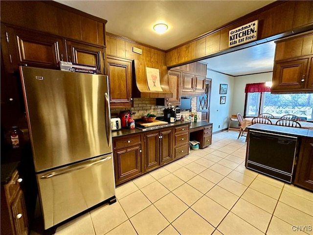 kitchen with light tile patterned flooring, crown molding, stainless steel fridge, black dishwasher, and decorative backsplash