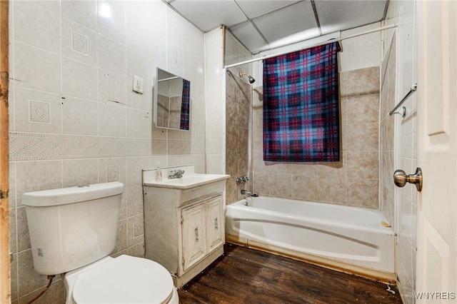 full bathroom featuring hardwood / wood-style floors, tile walls, shower / bath combination with curtain, vanity, and toilet