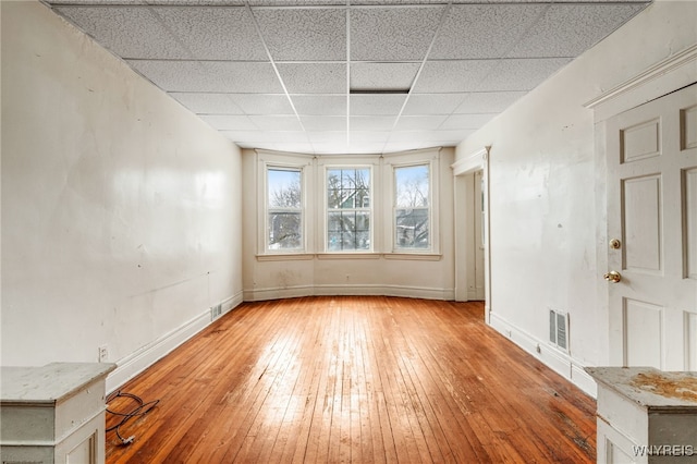 empty room with a paneled ceiling and light hardwood / wood-style flooring