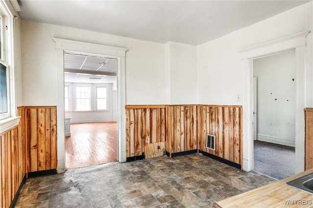 empty room with a drop ceiling and wood walls