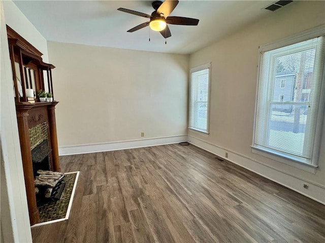 unfurnished living room with ceiling fan, dark wood-type flooring, and a fireplace