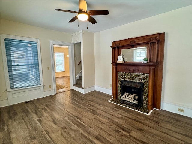 unfurnished living room featuring ceiling fan, dark hardwood / wood-style floors, and a tiled fireplace