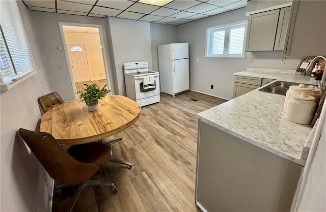 kitchen featuring a drop ceiling, white appliances, gray cabinets, and light wood-type flooring