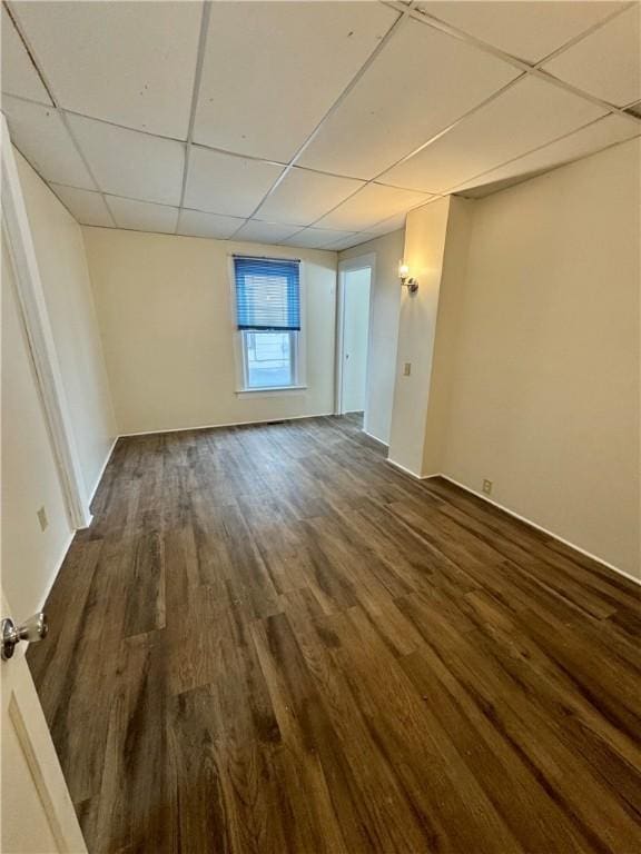 spare room with a drop ceiling and dark hardwood / wood-style flooring