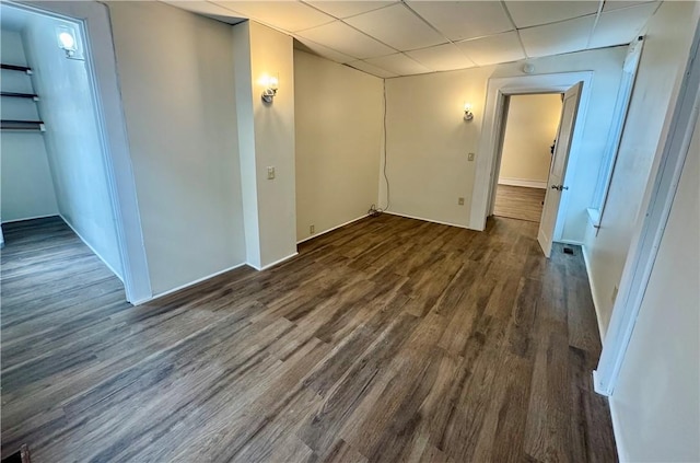 spare room featuring a drop ceiling and dark hardwood / wood-style flooring