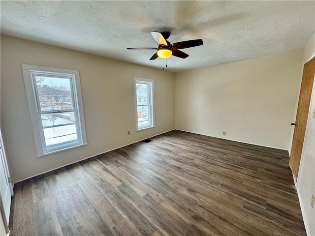 spare room with dark wood-type flooring, ceiling fan, and a healthy amount of sunlight