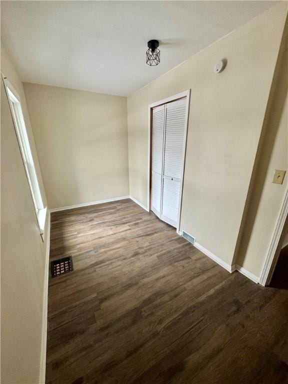 unfurnished bedroom with dark wood-type flooring and a closet