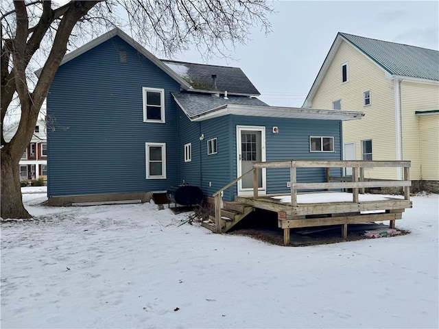 snow covered back of property featuring a wooden deck