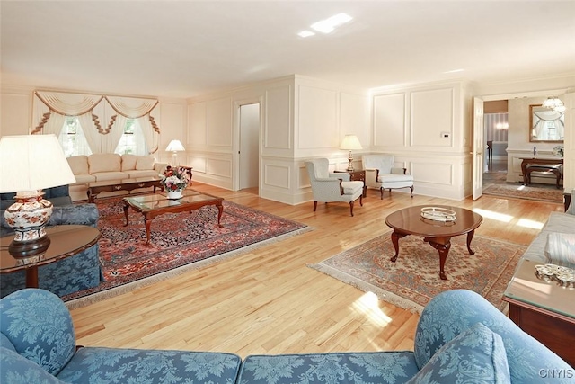 living room with ornamental molding, a notable chandelier, and light hardwood / wood-style flooring